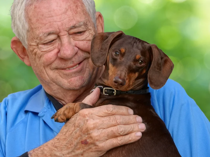enfoque-superficial-de-un-anciano-hombre-caucasico-sosteniendo-un-entranable-perro-dachshund